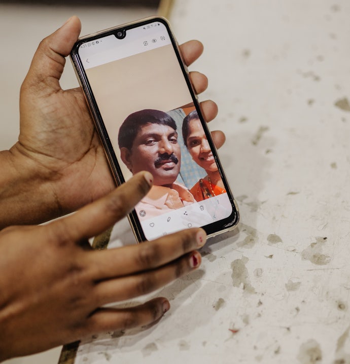 Sunitha viser fram foto av en frisk ektemann på mobiltelefonen sin.