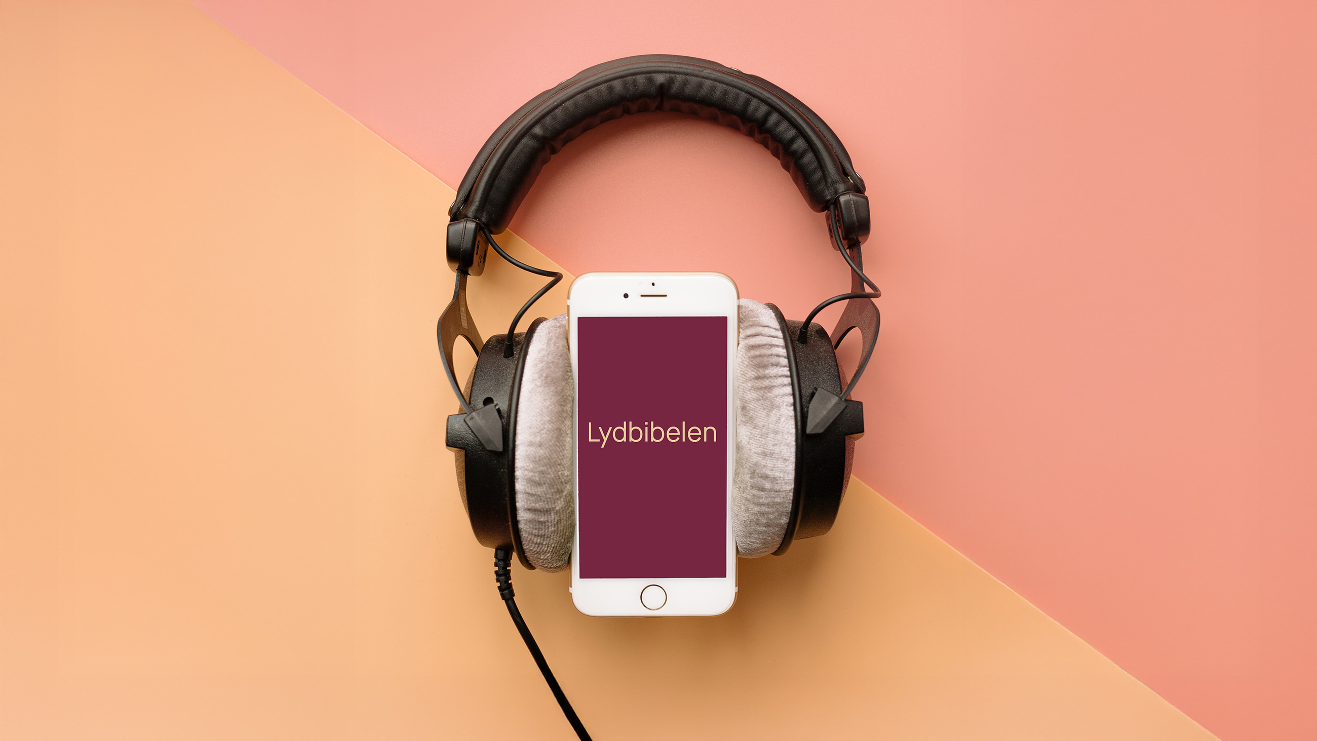 mobiletelefon med headset på, det står "lydbibelen" på mobilskjermen