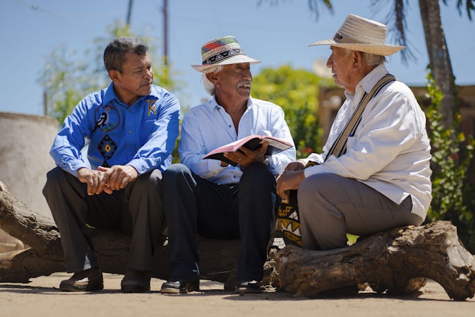 Tre venezuelanske menn i samtale over et åpent nytestamente
