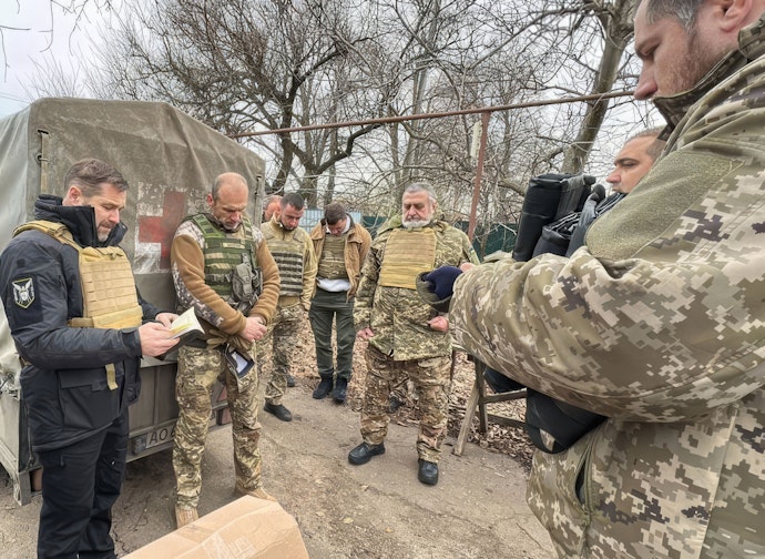 Assisterende generalsekretær Anatoliy Raychenets (til venstre) og styreleder Vasyl Lutsyshyn (midt i bildet) i Det ukrainske bibelselskapet tar seg helt fram til fronten for å betjene soldatene som kjemper der.