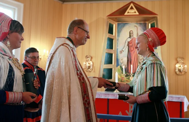 Biskop Olav Øygard blir overrakt Bibelen av Elle Karen Inga Skum. Hun har vært med i oversettelsesarbeidet, og representerte Bibelselskapet ved høytideligheten i Kautokeino kirke.