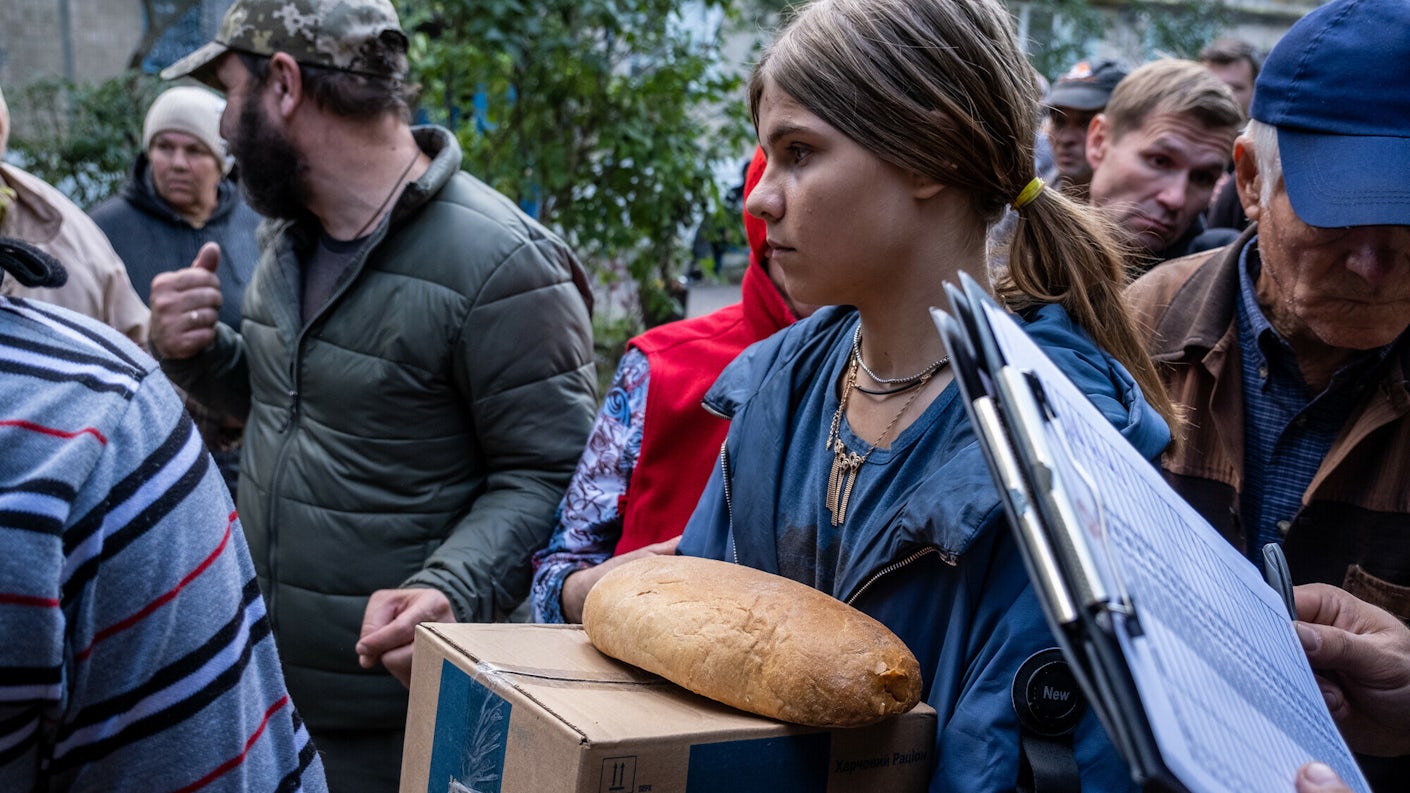 Jente i fokus foran en folkemengde som har mottatt brød, nødhjelp og bibler fra Bibelselskapet