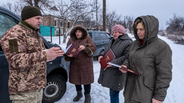 I en snølagt gate samtaler Bibelselskapets utsendte med tre kvinner som har fått hver sin bibel.